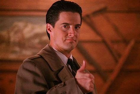 Special Agent Dale Cooper, from the TV show Twin Peaks, giving a thumbs up in a light brown trenchcoat. He has a disarmingly welcoming smile.